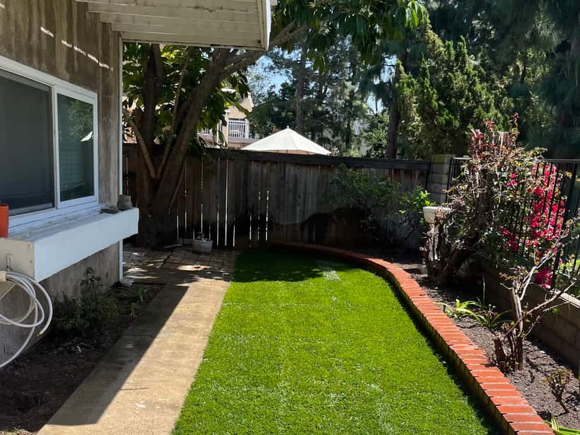 Narrow side yard laid in new grass with a brick edge