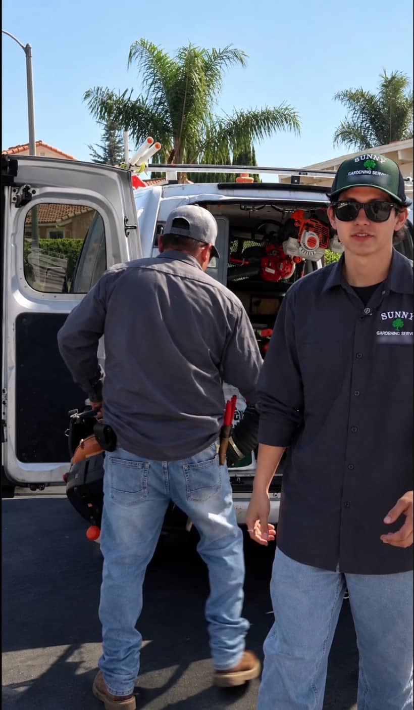 Two of the Sunny Gardening Service crew loading trimmers and blowers into the work van